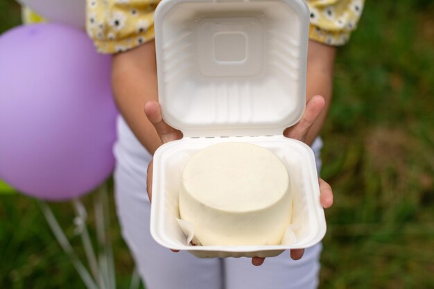 An open white box with a cream bento cake in the hands of a person