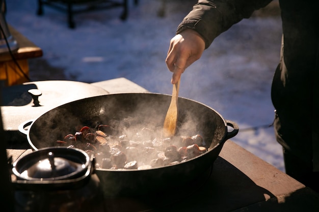 Openair kitchen frying homemade sausages in sauce