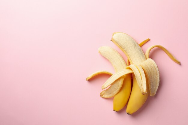 Opened bananas on pink background. Fresh fruit