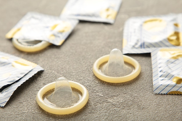 Opened condom and condom in pack on grey background A condom use to reduce the probability of pregnancy or sexually transmitted disease