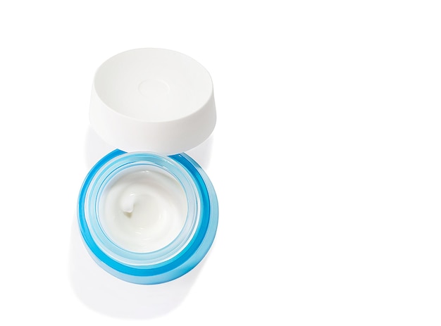 Opened cosmetic jar with cream on a white background. Body care creative concept.