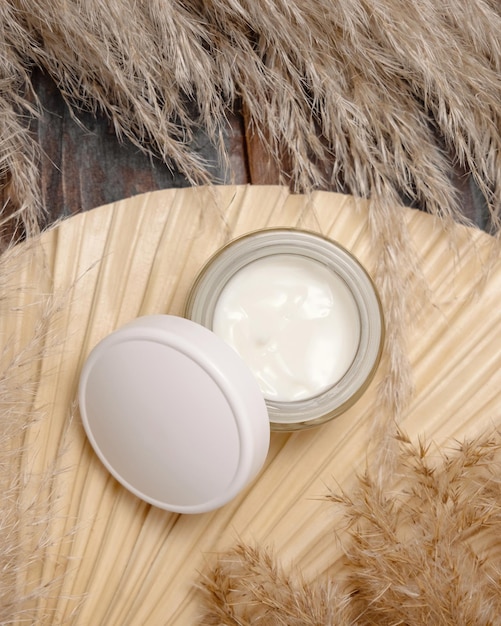 Opened cream jar with a blank lid on dried palm leaf near pampas grass Cosmetic Mockup