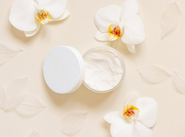 Opened Cream jar with a blank lid near orchid flowers on light beige top view Cosmetic Mockup