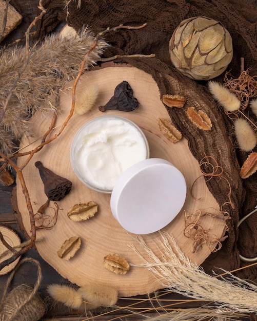 Opened cream jar with blank lid on wood near natural decorations top view Packaging Mockup