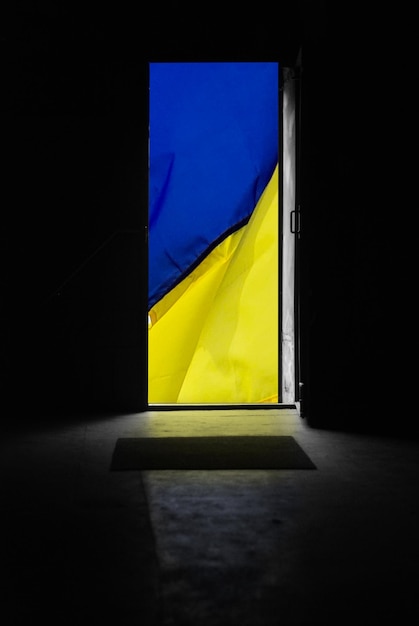 Opened door with ukrainian flag behind it