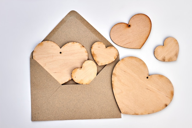 Opened envelope and plywood hearts. Vintage style envelope and wooden hearts on white background. Happy Valentines Day.