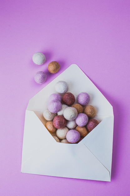 Opened envelope with colorful felt balls on purple background Minimal style Message concept