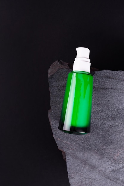 Opened green Bottle on stone isolated black background close up Brand packaging mockup