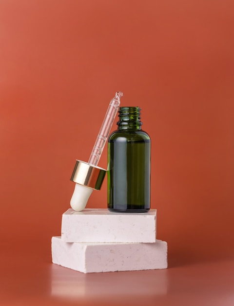 Opened Green dropper bottle on beige stone on red close up cosmetic Mockup