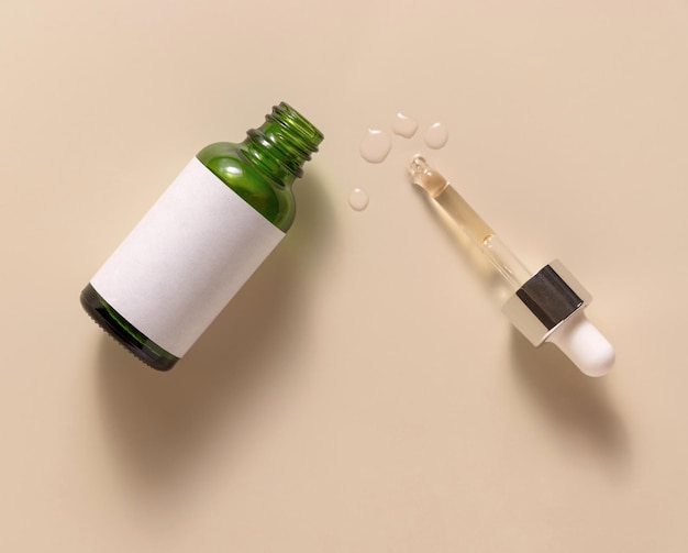 Opened Green dropper bottle with blank label on light beige top view cosmetic Mockup