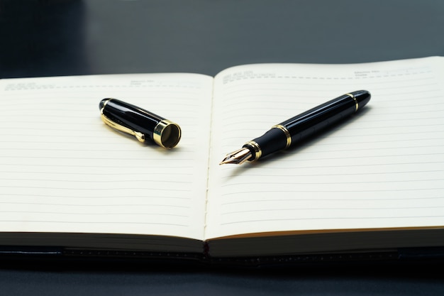 Opened lined diary notebook with a luxury pen with copy space