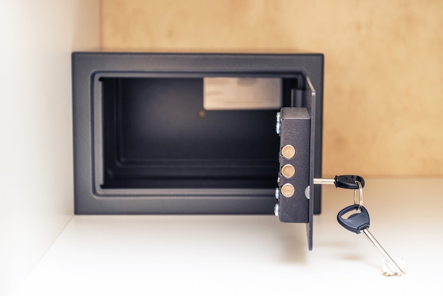 Opened metal safe with key and opened door in the hotel room,inside the cabinet