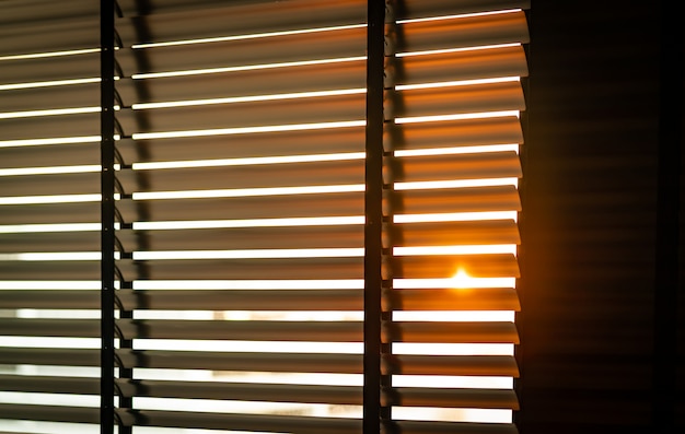 Opened venetian plastic blinds with sunlight in the morning. White plastic window with blinds. Interior design of living room with window horizontal blinds.