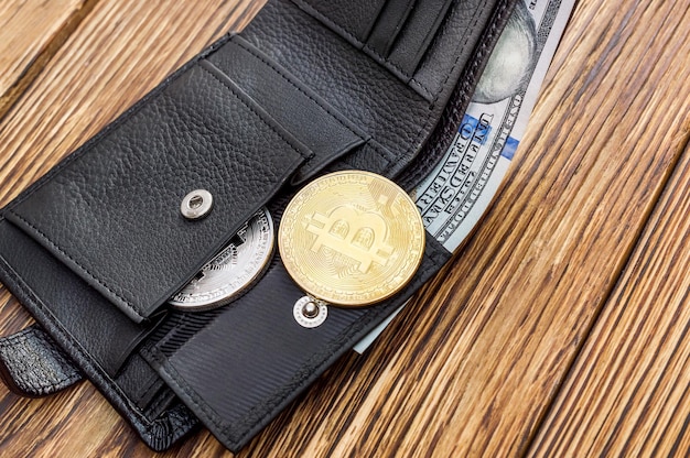 Opened wallet with coins of bitcoin and dollars on the table