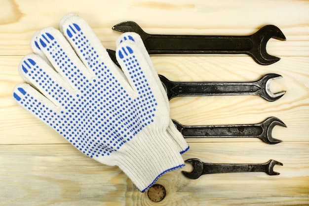 Openend wrenches and protective gloves on wooden tabl