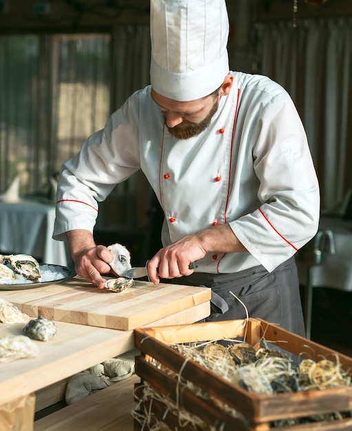 Opening the hollow and flat oysters. Chef opens oysters in the restaurant.