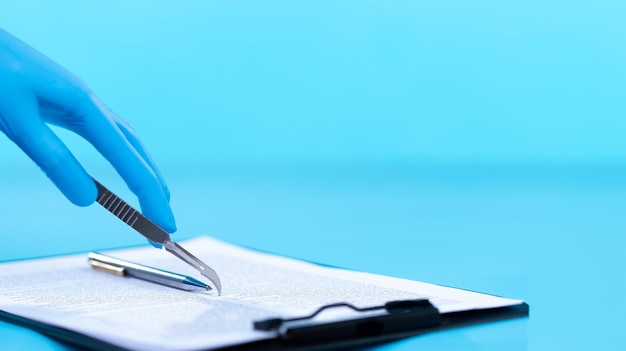 Operation being performed by a doctor while a Patient relative signs a document agreement with consent scalpel blade used as a pen for lawyer legal documents insurance and protection copy space