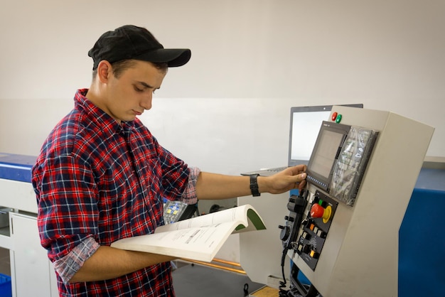 An operator of cnc is at work near the panel of management a machinetoolxA