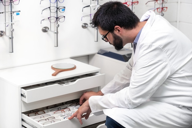  ophthalmologist choosing glasses from a drawer in the optical store