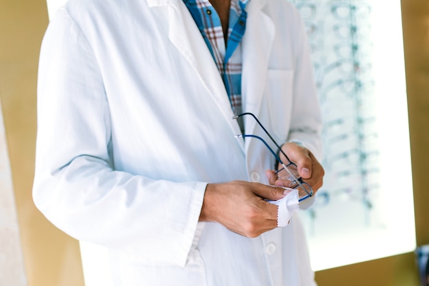 Ophthalmologist holding eyeglasses frame in optical store.