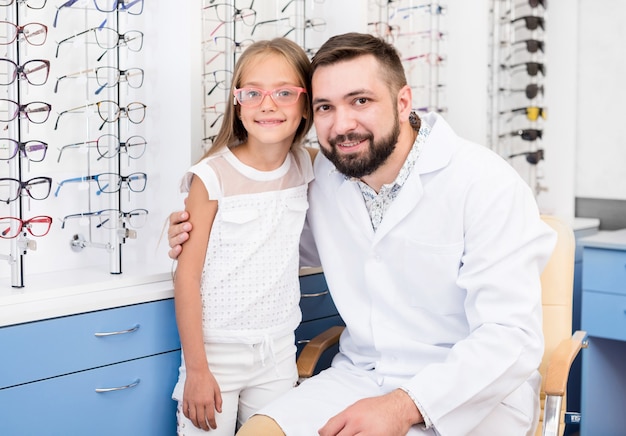 Ophthalmologist posing with little girl at optical clinic