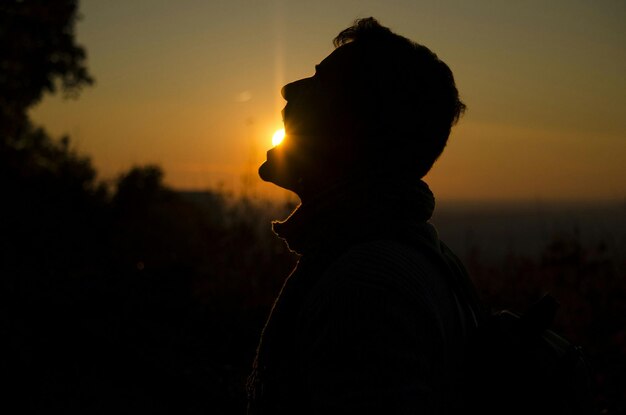 Photo optical illusion of silhouette man eating sun during sunset