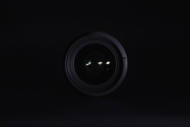 Optics to the camera on the operatorâs desk. Flare in the glass of a photo lens. Black background with the technique of the photographer.