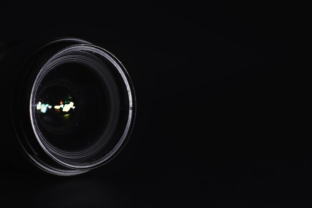 Photo optics to the camera on the operatorâs desk. flare in the glass of a photo lens. black background with the technique of the photographer.