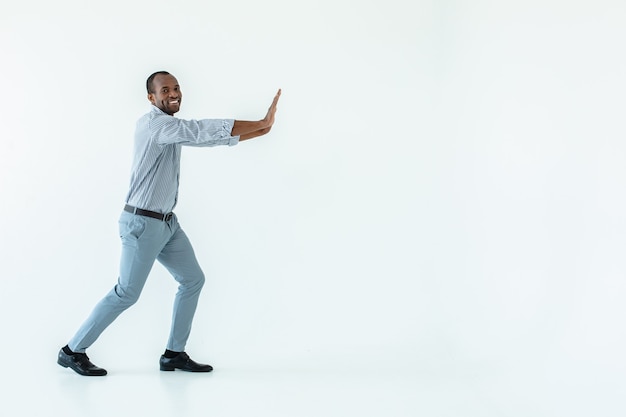 Optimistic afro american man pushing the block against white wall