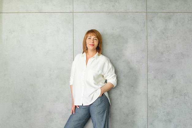 Photo optimistic friendly mature business woman in white shirt standing on grey banner background