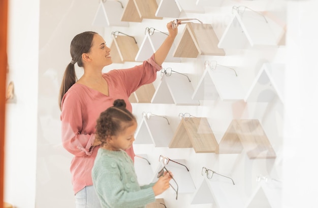 Optometry vision and mother with child make glasses choice shopping in a retail store for eye care Healthy eyesight ophthalmology and woman with girl buying eyewear and frame with lens