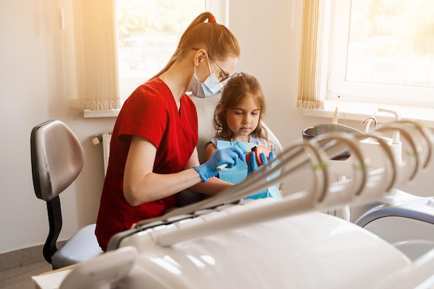 Oral hygiene lesson of jaw anatomical model for child in dentistry Dentist shows child how to properly brush his teeth with a toothbrush