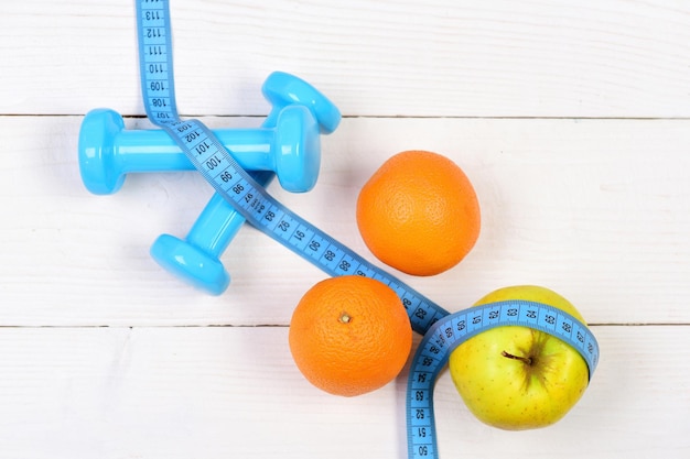 Orange apple with measuring tape weight dumbbells for diet concept