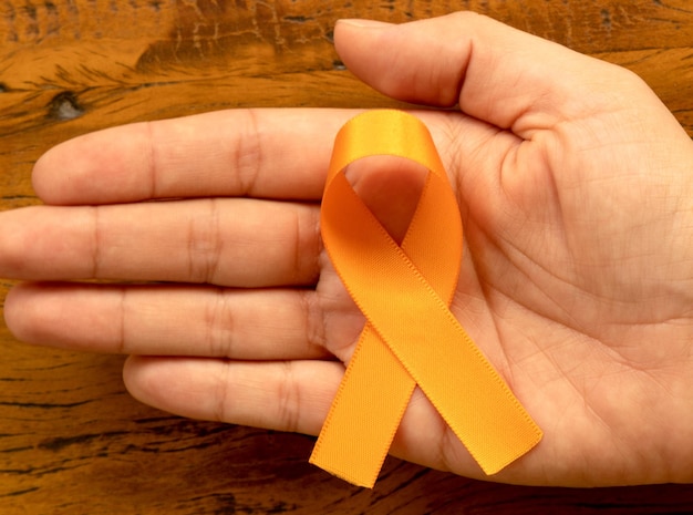 Orange august Multiple Sclerosis Awareness Campaign Hand holding orange ribbon