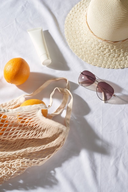 Orange bag with glasses, sun cream, straw hat on the sunset picnic.