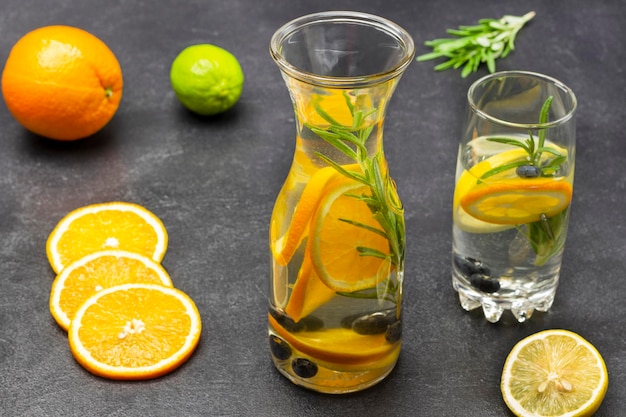 Orange blueberries and rosemary infused water in glass and bottle