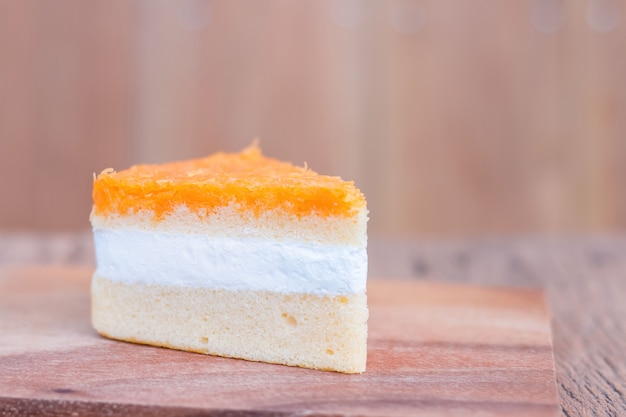 Orange cake pieces, golden threads on wooden table