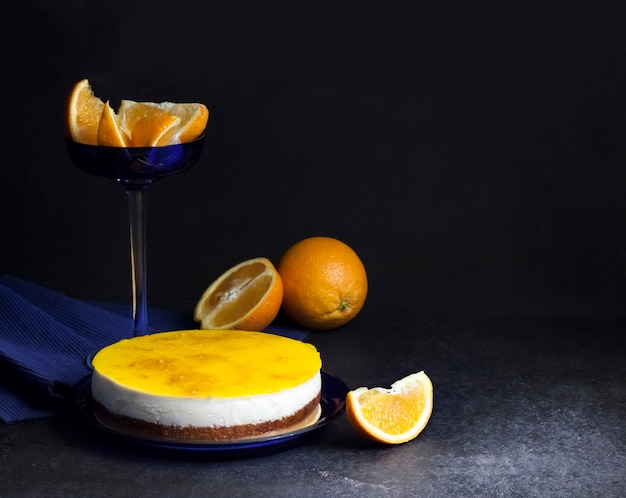 Orange cake with cream mousse and orange jelly on dark background