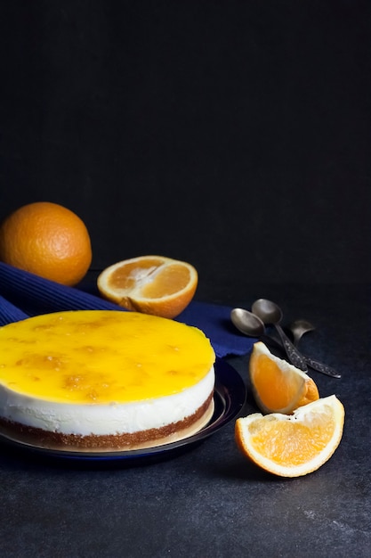 Orange cake with cream mousse and orange jelly on dark background