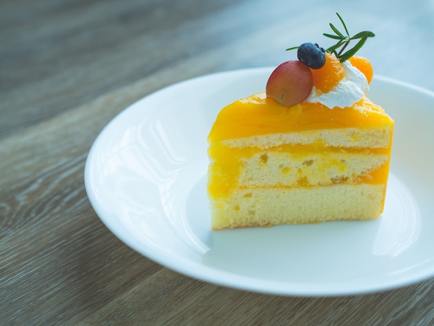 Orange cake with topping mix fruit  on white plate