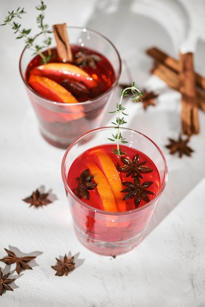 Orange cocktail with rum liquor pear slices and thyme on white table selective focus