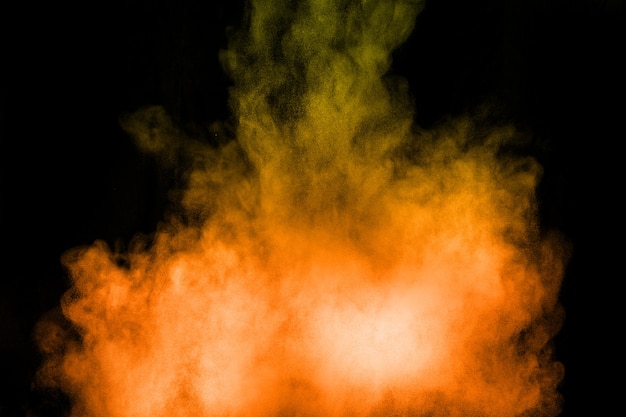 Orange color powder explosion on black background.