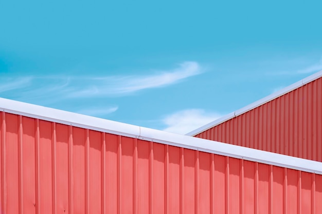 Orange corrugated steel rooftop of industrial buildings against blue sky in pastel color tone style