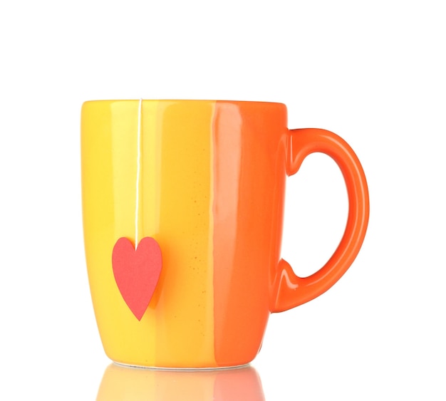 Orange cup and tea bag with red heart-shaped label isolated on white