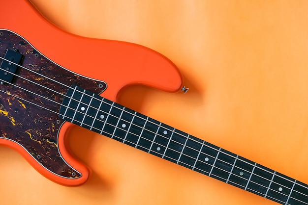 orange electric bass guitar on orange background with copy space