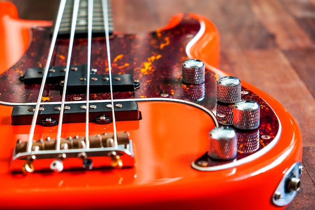 orange electric bass guitar on wood background with copy space