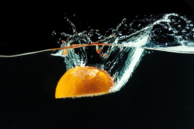 Orange falls into the water and making splashes