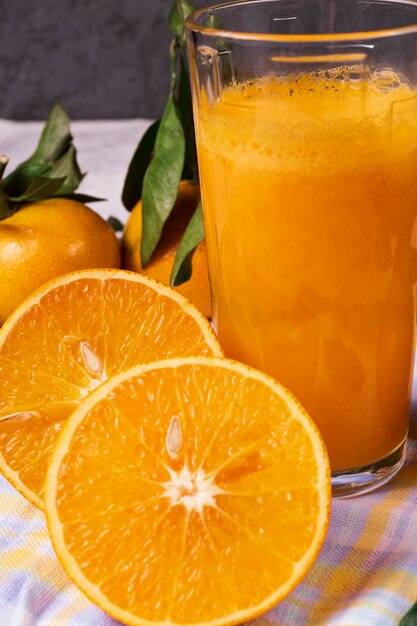 Orange fruit and some juice in a glass, over rustic background, closeup.