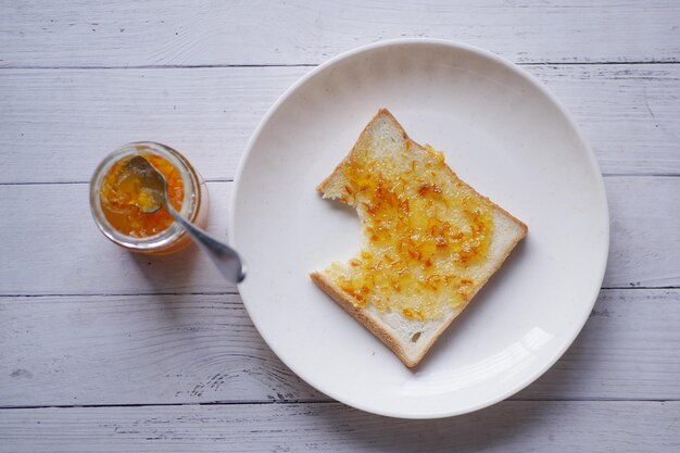 Orange fruit spread on a bread on table