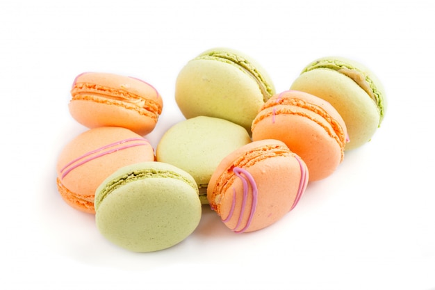 Orange and green macarons or macaroons cakes isolated on white background, side view.